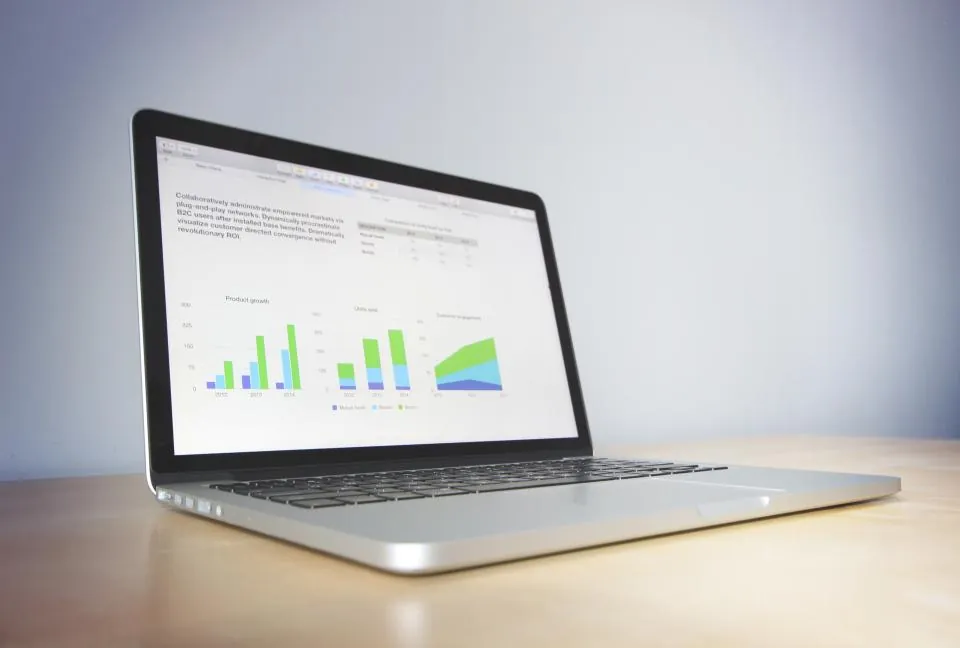 A laptop on a desk showing bar and area charts