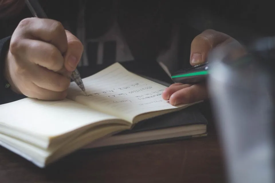 A hand writing in a notebook